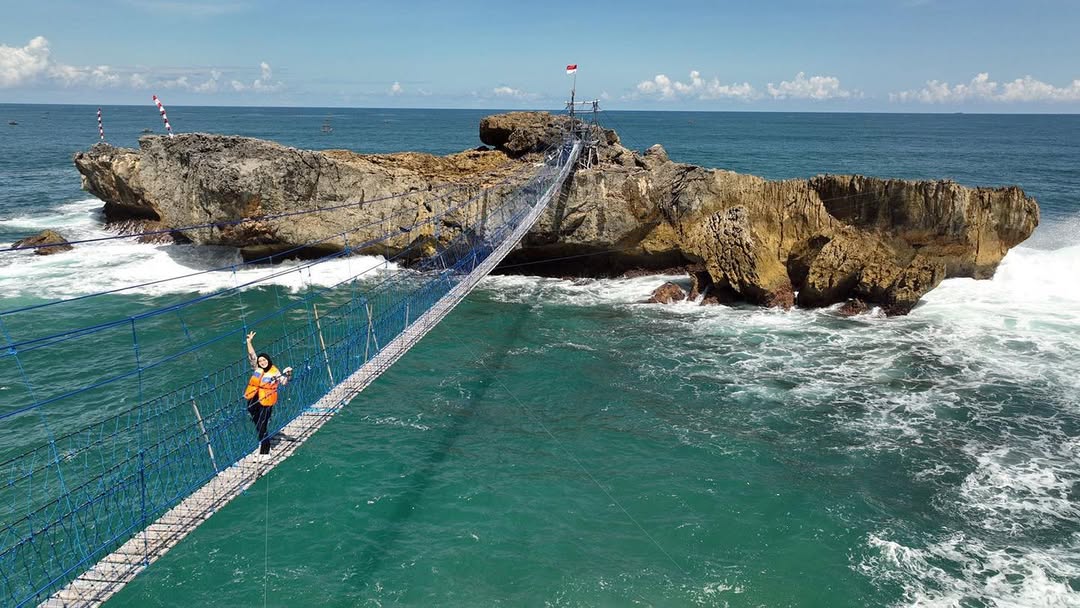Pengunjung melintasi jembatan gantung menuju batu karang di kawasan Pantai Watu Bale, Pacitan. (Foto:Instagram @dfnata)